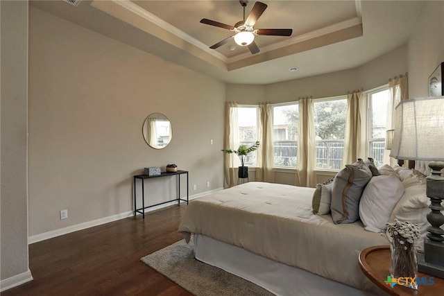 bedroom featuring dark hardwood / wood-style floors, ornamental molding, a raised ceiling, and ceiling fan