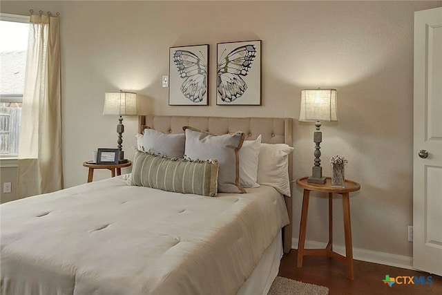 bedroom with multiple windows and dark hardwood / wood-style flooring