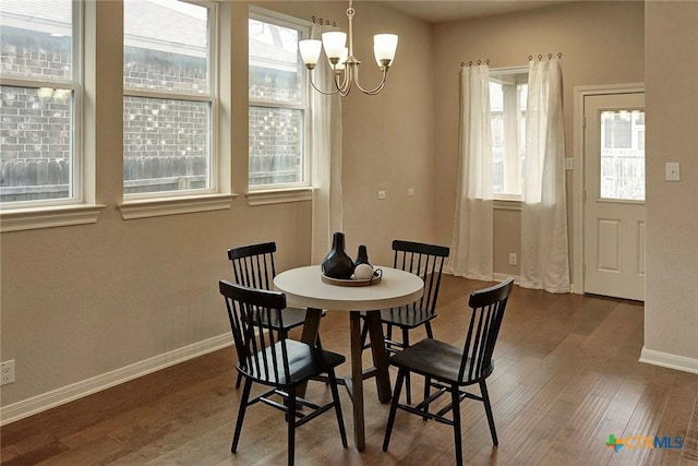 dining area with dark hardwood / wood-style floors, a wealth of natural light, and an inviting chandelier