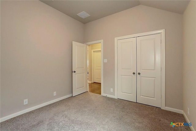 unfurnished bedroom featuring light colored carpet, vaulted ceiling, and a closet