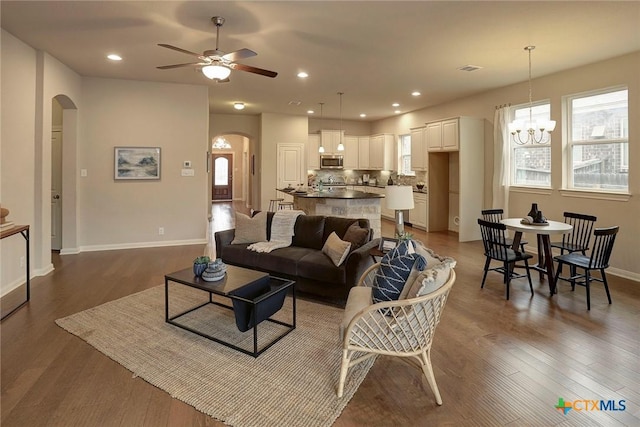 living room featuring dark hardwood / wood-style flooring and ceiling fan with notable chandelier