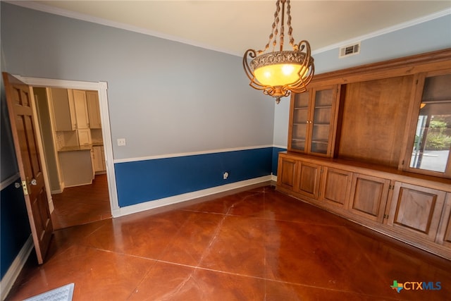 unfurnished dining area featuring a notable chandelier, dark tile patterned flooring, and ornamental molding