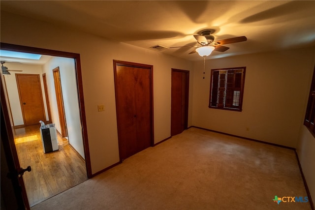 unfurnished bedroom with a skylight, light colored carpet, and ceiling fan