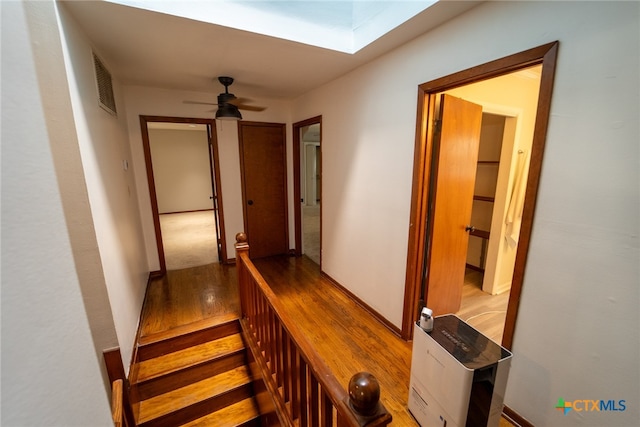 stairway featuring hardwood / wood-style floors, ceiling fan, and a skylight