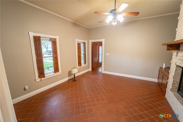 unfurnished living room featuring dark tile patterned floors, crown molding, ceiling fan, and a fireplace