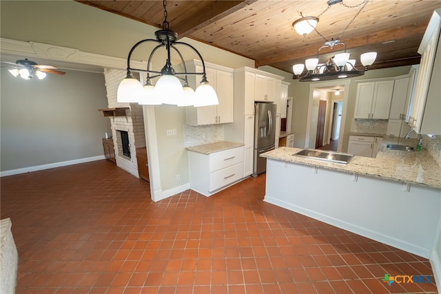 kitchen with white cabinets, decorative backsplash, decorative light fixtures, and stainless steel fridge