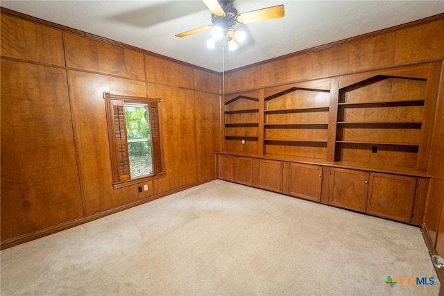 carpeted spare room with wood walls and ceiling fan