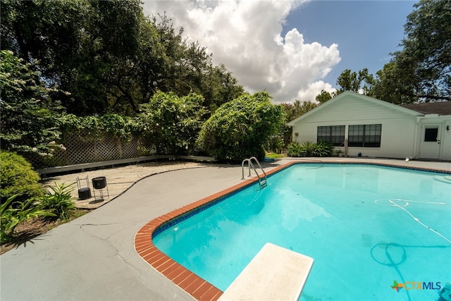 view of swimming pool with a diving board and a patio