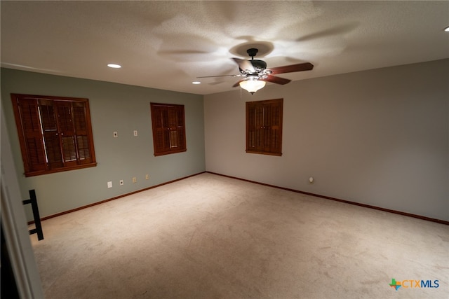 spare room featuring a textured ceiling, light colored carpet, and ceiling fan