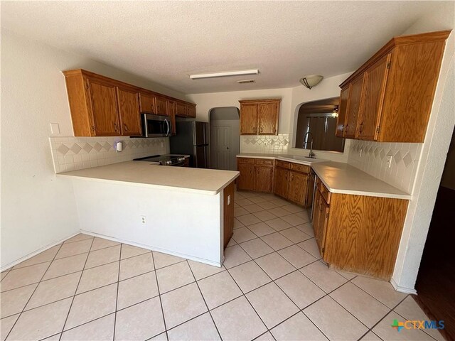 3054 Colorado Dr, Copperas Cove, TX 76522 - kitchen with arched walkways, stainless steel microwave, decorative backsplash, a peninsula, and a textured ceiling