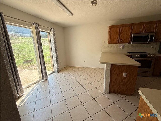 3054 Colorado Dr, Copperas Cove, TX 76522 - kitchen featuring stainless steel appliances, light countertops, a peninsula, light tile patterned floors, and tasteful backsplash