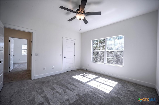 unfurnished bedroom with multiple windows, dark colored carpet, and ceiling fan