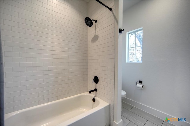 bathroom with tile patterned floors, tiled shower / bath combo, and toilet