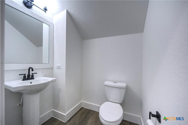 bathroom featuring toilet, sink, and vaulted ceiling