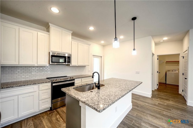 kitchen with stainless steel appliances, sink, decorative light fixtures, a center island with sink, and white cabinets