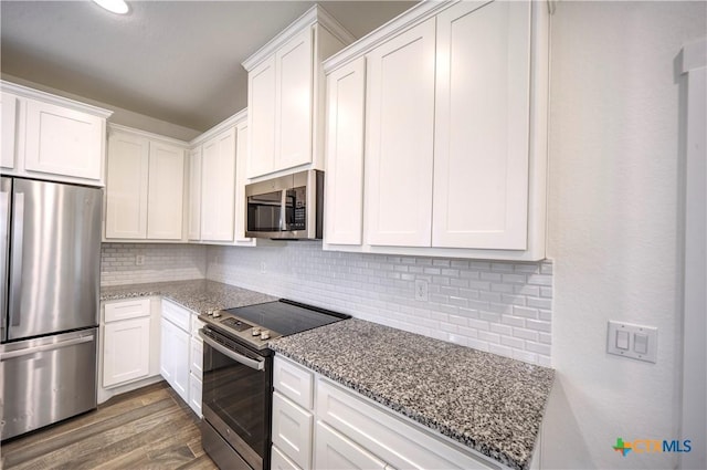 kitchen featuring decorative backsplash, white cabinetry, light stone countertops, and appliances with stainless steel finishes