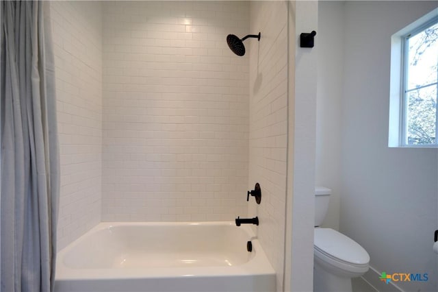 bathroom featuring tiled shower / bath combo and toilet