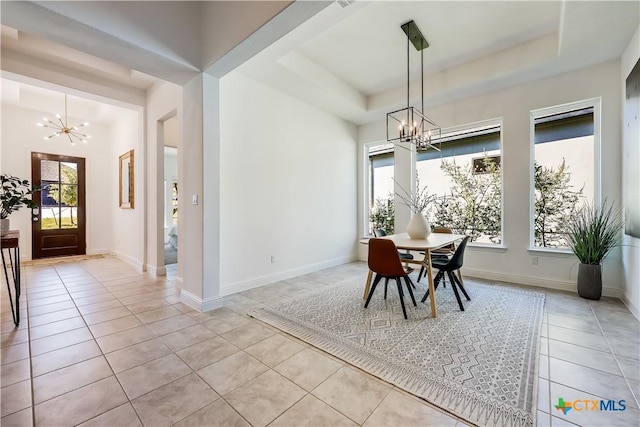 dining area featuring an inviting chandelier, a raised ceiling, and light tile patterned flooring