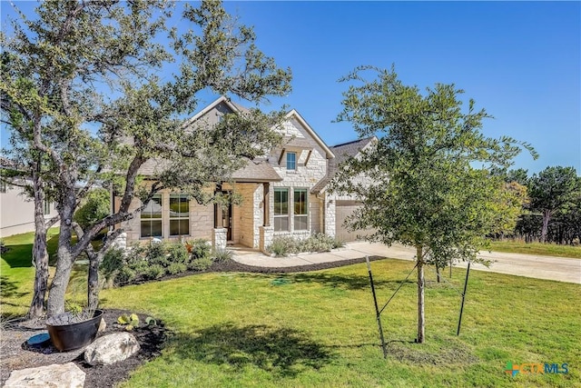 view of front of house featuring a garage, a front yard, stone siding, and driveway