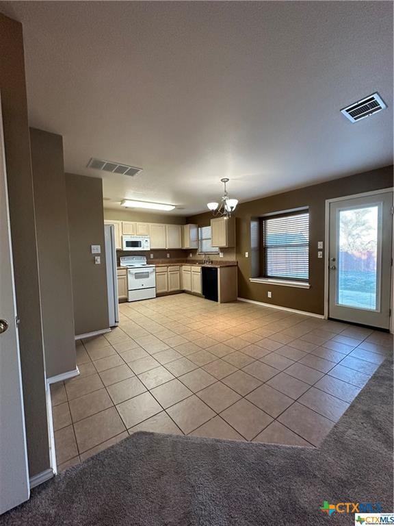 kitchen featuring a notable chandelier, light tile patterned floors, baseboards, white appliances, and visible vents
