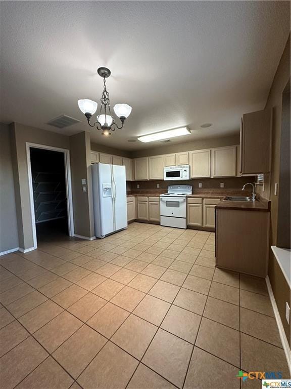 kitchen featuring hanging light fixtures, white appliances, light tile patterned flooring, a sink, and a chandelier