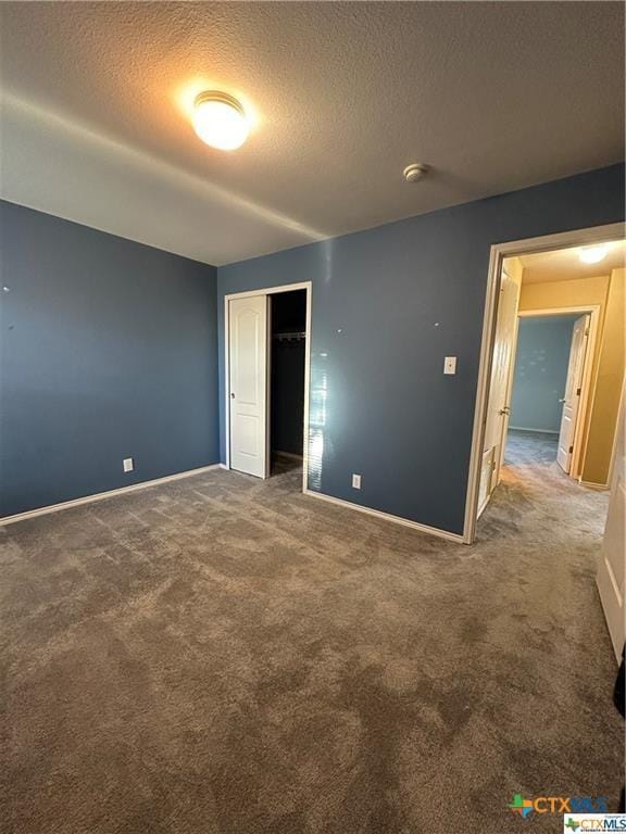 unfurnished bedroom featuring a textured ceiling, carpet, and baseboards