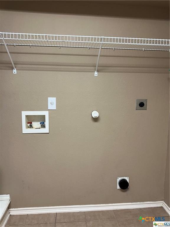 clothes washing area with laundry area, hookup for an electric dryer, tile patterned flooring, washer hookup, and baseboards