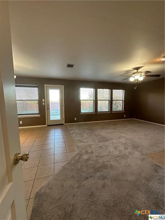 unfurnished living room with a healthy amount of sunlight, ceiling fan, light tile patterned flooring, and visible vents