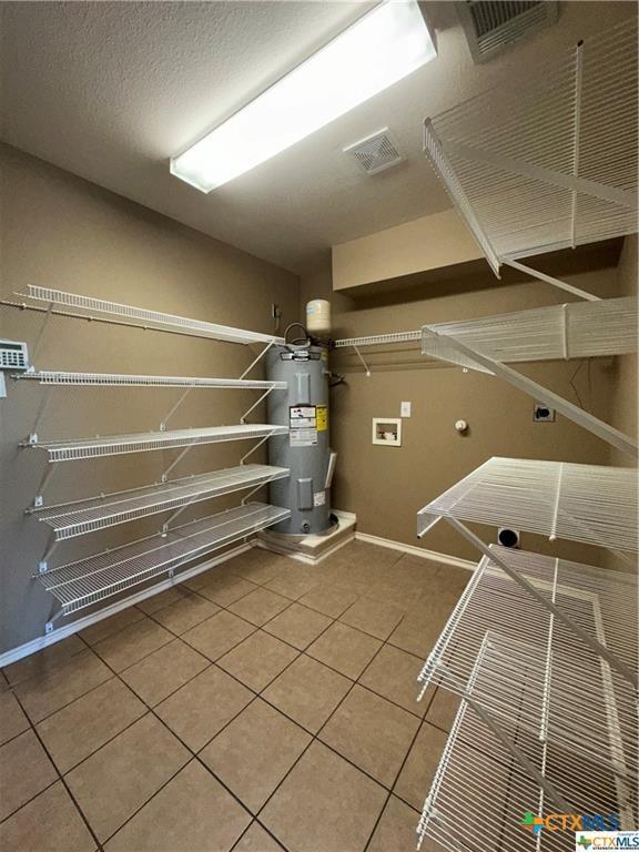laundry room featuring hookup for a washing machine, tile patterned flooring, electric water heater, hookup for an electric dryer, and laundry area