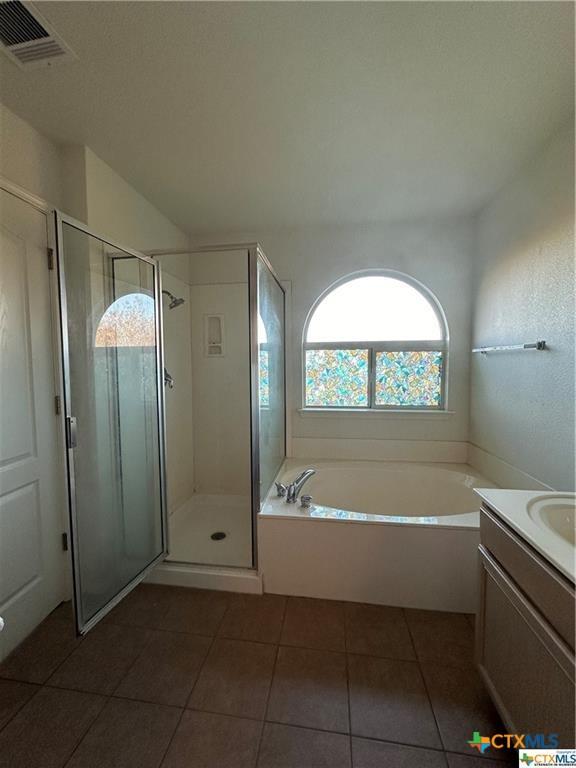 bathroom featuring tile patterned floors, visible vents, a stall shower, and a bath