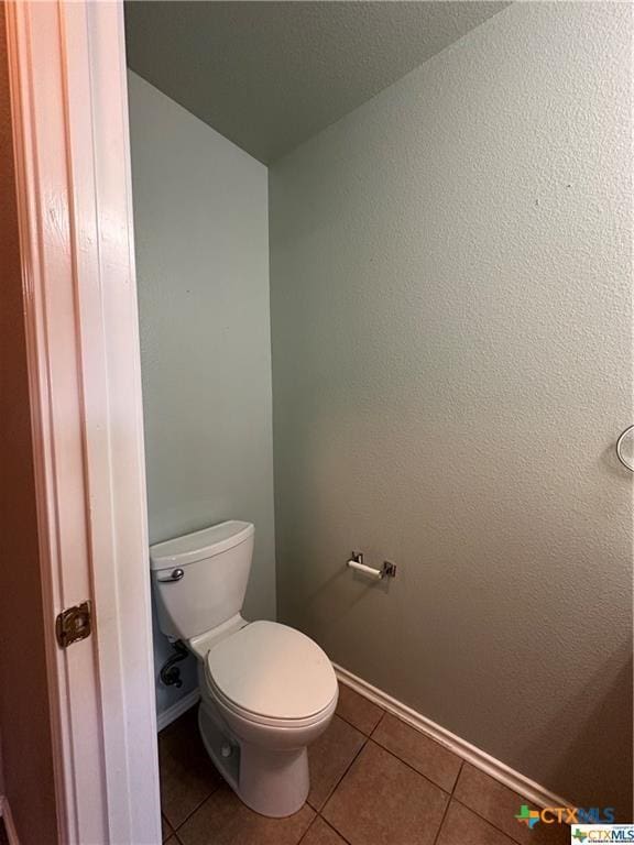 bathroom featuring toilet, tile patterned flooring, and baseboards