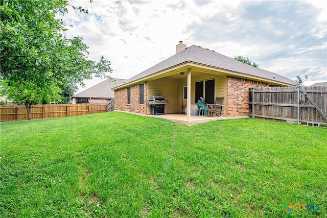 back of property with a chimney, a patio, brick siding, and a fenced backyard