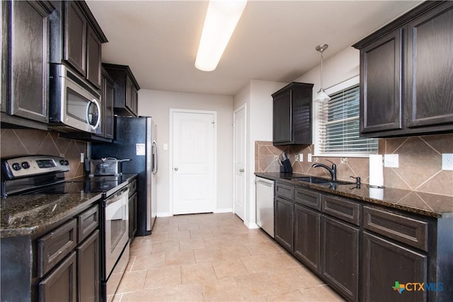 kitchen featuring stainless steel appliances, dark stone countertops, a sink, and decorative backsplash
