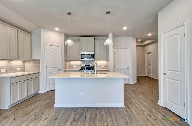 kitchen featuring sink, hanging light fixtures, decorative backsplash, light hardwood / wood-style floors, and stainless steel appliances