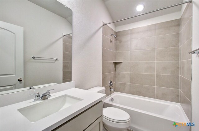 full bathroom featuring tiled shower / bath combo, toilet, and vanity