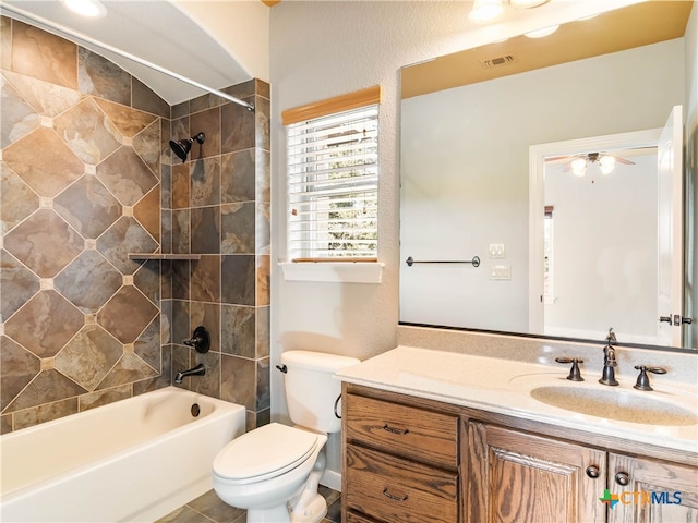 full bathroom featuring ceiling fan, vanity, toilet, and tiled shower / bath