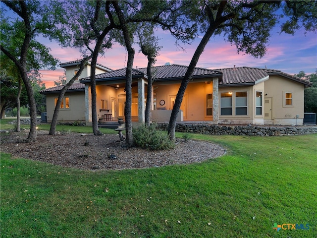 view of front of property with central AC unit and a yard