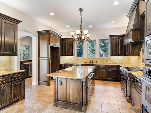 kitchen with a kitchen island, pendant lighting, dark brown cabinetry, and plenty of natural light