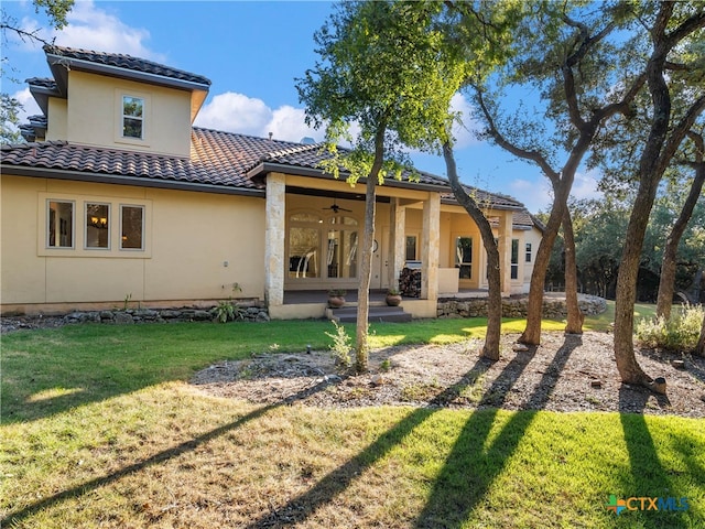 rear view of property with a patio, ceiling fan, and a yard