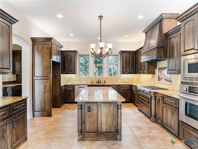 kitchen with stainless steel appliances, dark brown cabinetry, custom range hood, a kitchen island, and pendant lighting