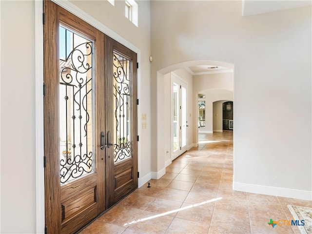 tiled foyer entrance featuring crown molding and french doors