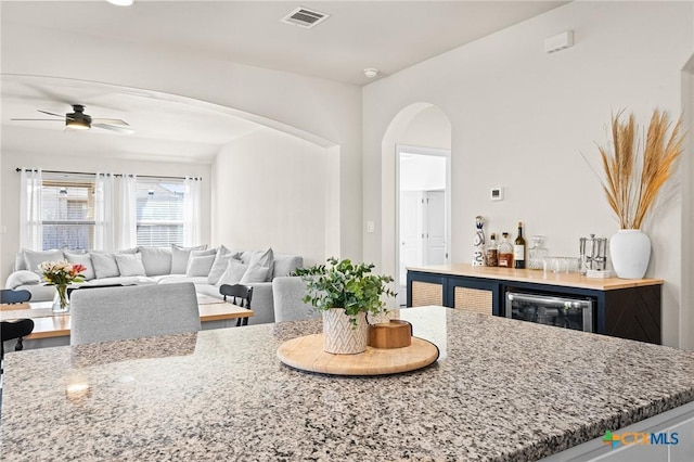 dining room with indoor bar, ceiling fan, and beverage cooler