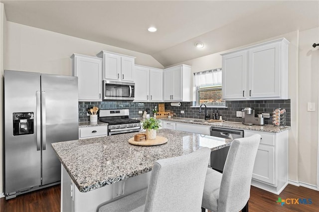 kitchen with appliances with stainless steel finishes, white cabinetry, a breakfast bar area, and a kitchen island