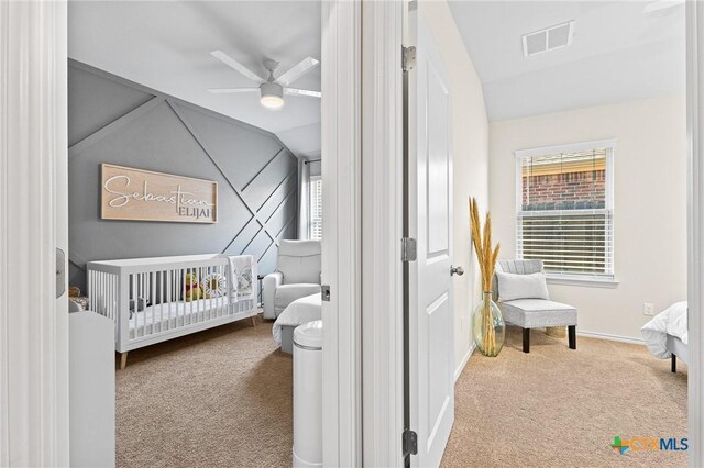 bedroom featuring vaulted ceiling, ceiling fan, a crib, and carpet