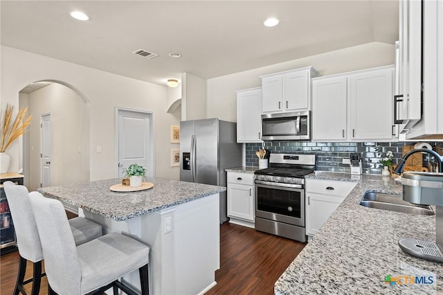 kitchen with sink, stainless steel appliances, white cabinetry, and a center island