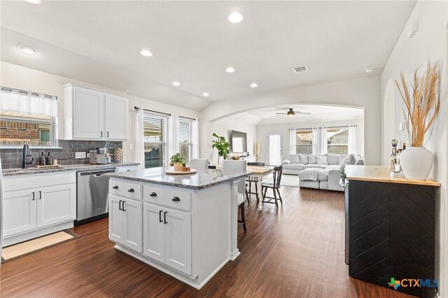 kitchen featuring light stone counters, stainless steel dishwasher, a center island, white cabinets, and ceiling fan