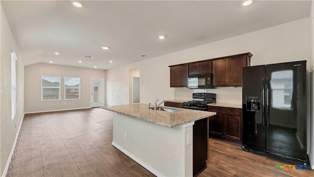 kitchen featuring light stone countertops, sink, black appliances, a center island with sink, and dark hardwood / wood-style floors