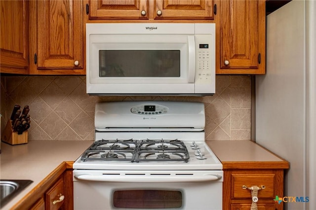 1617 Avalon St, Port Lavaca, TX 77979 - kitchen featuring white appliances, backsplash, brown cabinets, and light countertops
