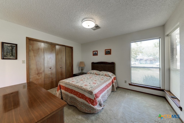 carpeted bedroom with a textured ceiling and a closet