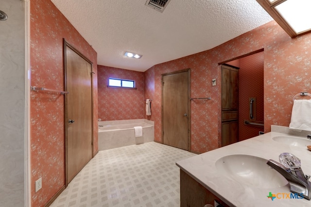 bathroom featuring a tub to relax in, vanity, and a textured ceiling